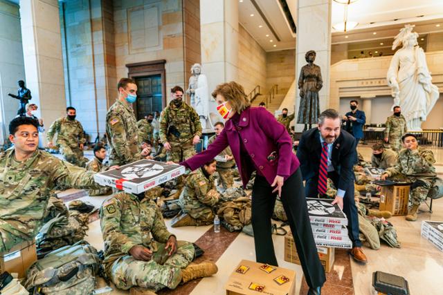 도널드 트럼프 미국 대통령에 대한 두번 째 탄핵소추안이 하원에서 가결된 13일 미국 워싱턴DC 의회에서 비키 하츨러공화미주리 하원의원과 마이크 왈츠공화플로리다 하원의원이 의회 방문객센터에 모여 있는 주방위군들에게 피자를 나눠주고 있다 